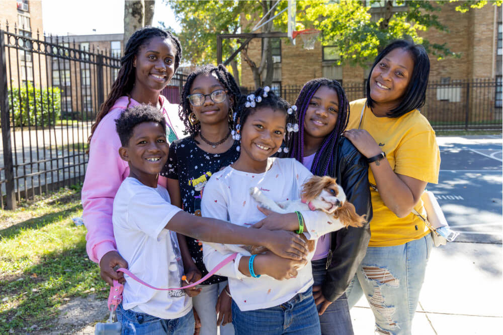 A family of several generations of African American women posing with their dog and smiling.