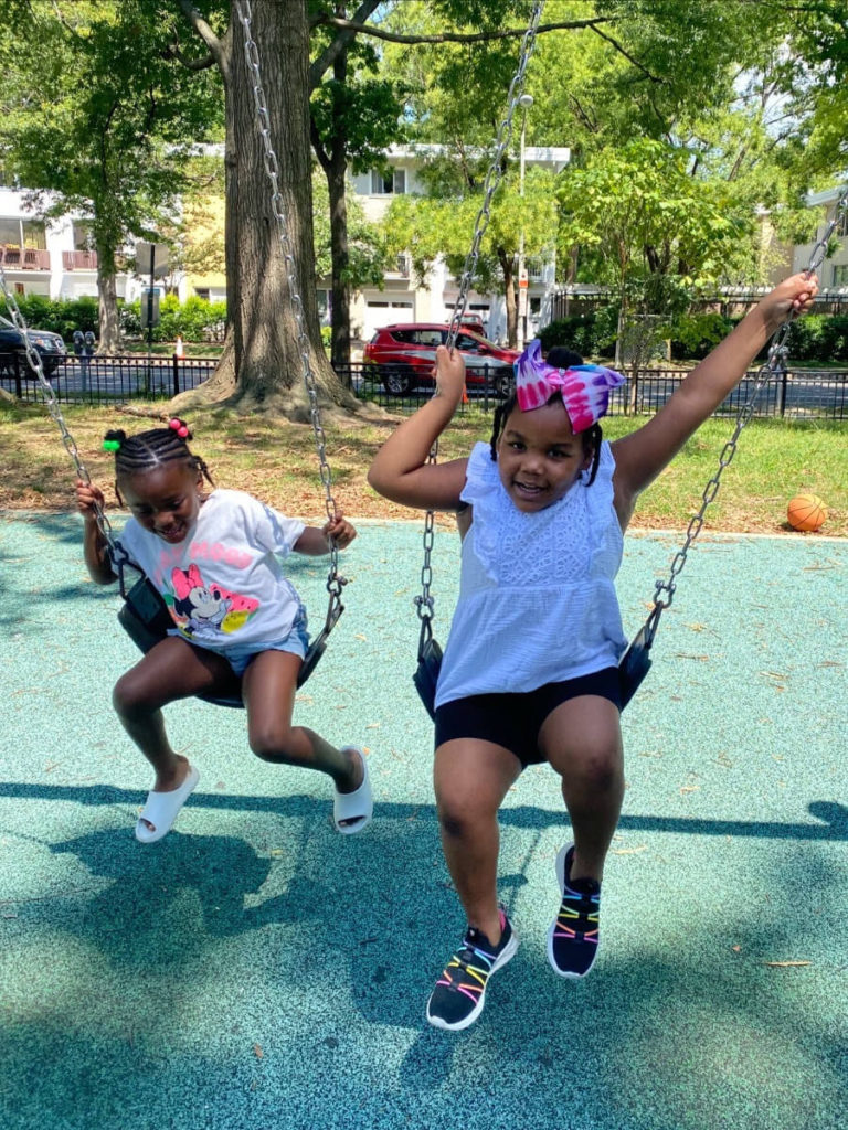 Two girls playing on a swingset.